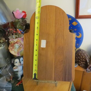 May include: A wooden cutting board with a rounded top and a brass stand. The board is 15 inches tall and has a label that reads "Danish".