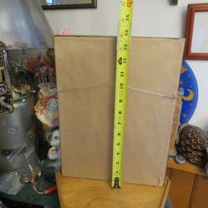 May include: The back of a framed picture with a brown mat and a wood frame. The frame is 15 inches tall.