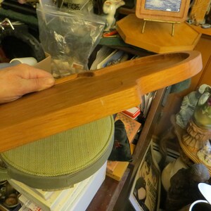 May include: A long, wooden serving tray with a rounded edge. The tray is made of light brown wood and has a smooth, polished finish.
