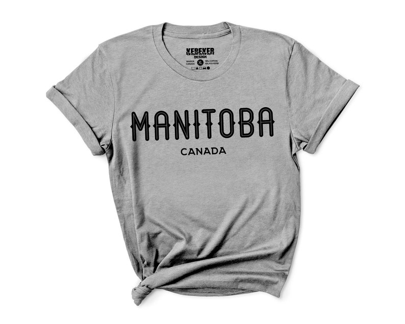 May include: A heather gray t-shirt with the word "MANITOBA" in black, arched text, and "CANADA" below it. The shirt has rolled-up sleeves and a crew neck. The brand name "XEREKER DESIGN" is printed at the top.