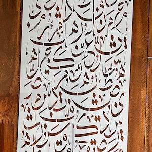May include: A white stencil with a design of Arabic calligraphy. The stencil is made of a thin, flexible material and is designed for use with paint or other mediums.