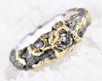 May include: A silver ring with a textured surface and gold accents. A single clear diamond is set in the center of the ring.