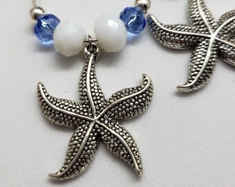 May include: A pair of silver hoop earrings with blue and white beads and a silver starfish charm.