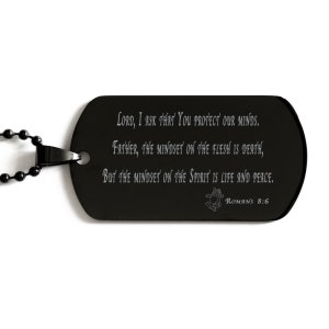Puede incluir: Collar con placa de identificación de metal negro con una inscripción plateada que dice "Señor, te pido que protejas nuestras mentes. Padre, la mentalidad en la carne es la muerte, pero la mentalidad en el espíritu es vida y paz. Romanos 8:6"