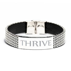 Può includere: Un braccialetto color argento con la parola "THRIVE" incisa su una placca rettangolare. Il braccialetto presenta un design a rete con piccole perforazioni circolari e un interno nero. Ha una chiusura a fermaglio sicura.
