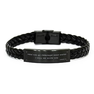 Può includere: Bracciale in pelle intrecciata nera con chiusura in acciaio inossidabile. Il bracciale presenta una placca rettangolare con il testo inciso: "WHEN YOU GO THROUGH DEEP WATERS I WILL BE WITH YOU" e "ISAIAH 43:2".