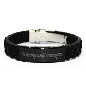 May include: Black silicone bracelet with a silver clasp and a black metal plate engraved with the words "Be strong and courageous" and "Deut 31:6".