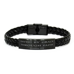 Puede incluir: Pulsera trenzada de cuero negro con una placa de metal plateado que dice "SAVED BY GRACE THROUGH FAITH EPHESIANS 2:8".