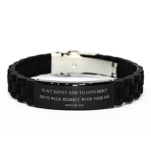 Pode incluir: Pulseira de silicone preta com fecho prateado e uma placa de metal preta gravada com o texto "TO ACT JUSTLY AND TO LOVE MERCY AND TO WALK HUMBLY WITH YOUR GOD. MICAH 6:8"