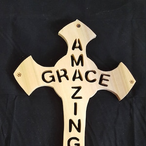 Beautiful handmade cross with the words amazing grace cut out of the wood