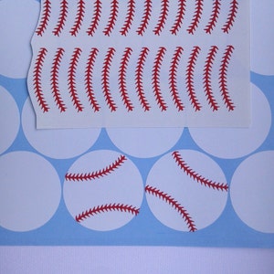 May include: A sheet of white sticker paper with red baseball stitch designs. There are two baseball stickers with red stitches on white circles.