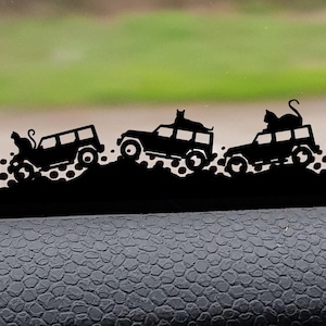 May include: A black silhouette of three jeeps driving in a line. Each jeep has a cat sitting on top of it. The jeeps are driving on a black and white chequered background.
