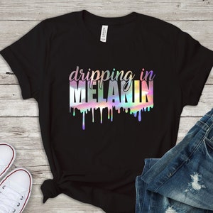 May include: Black t-shirt with a holographic design that says "dripping in melanin".