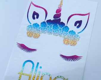 May include: A rainbow glitter unicorn with a flower crown and eyelashes. The name "Alina" is written below the unicorn in rainbow glitter.