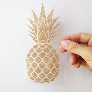 Puede incluir: Pegatina de piña con purpurina dorada. La piña está contorneada en blanco y tiene un acabado de purpurina texturizado.