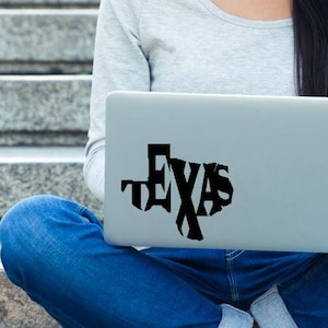 Może przedstawiać: Laptop z czarną naklejką winylową przedstawiającą stan Teksas z napisem "TEXAS" napisanym w kształcie stanu.