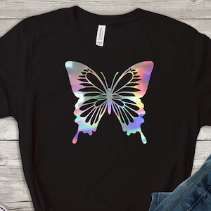 May include: A black t-shirt with a holographic butterfly design. The butterfly is iridescent with shades of pink, blue, and green.