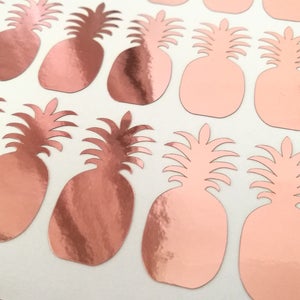 Könnte beinhalten: Eine Blatt mit Ananas-Aufklebern in Roségold. Die Ananas sind ausgeschnitten und haben eine glänzende, metallische Oberfläche.