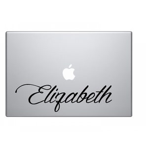 Op de afbeelding: Een zilveren laptop met een zwart Apple-logo en de naam "Elizabeth" in cursief op de deksel.