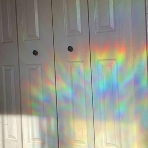 May include: White closet doors with a rainbow prism light reflection on the surface.