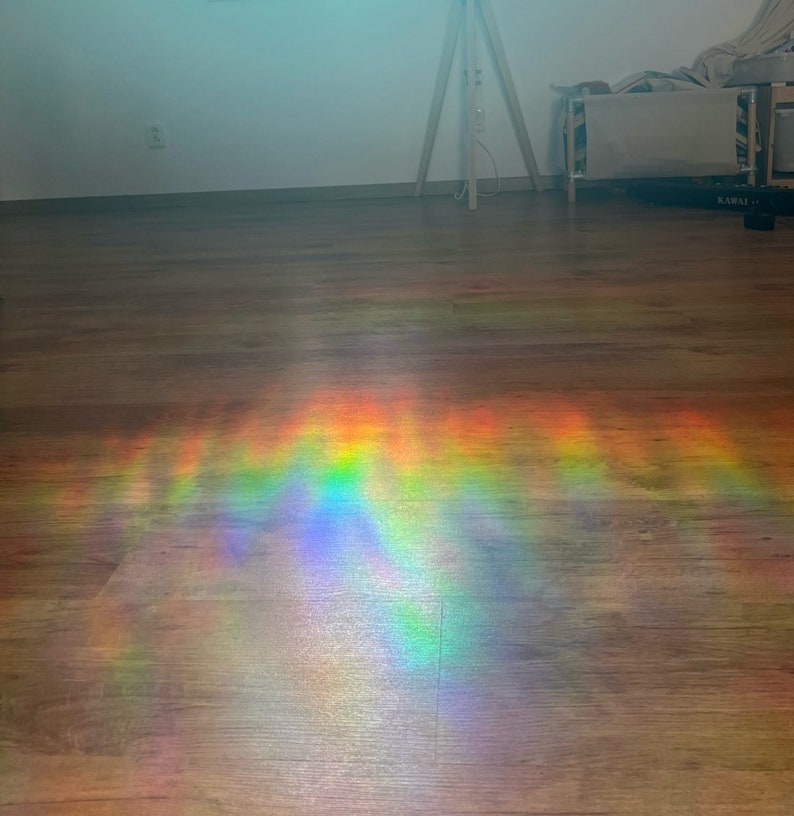 May include: A rainbow prism effect is cast on a wooden floor, creating a colourful and abstract pattern of light.
