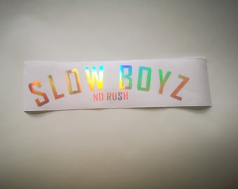 May include: A white sticker with iridescent rainbow lettering that reads "SLOW BOYZ NO RUSH".