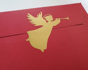 May include: A gold angel silhouette with wings and a trumpet, on a red envelope.