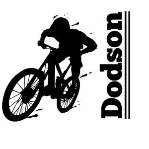 Op de afbeelding: Silhouet van een persoon die op een mountainbike rijdt met de naam Dodson verticaal gedrukt aan de rechterkant van de afbeelding.