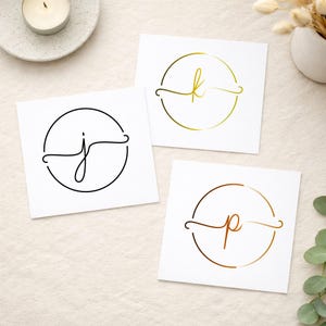 Puede incluir: Tres tarjetas cuadradas blancas con logotipos circulares y letras cursivas. Una tarjeta muestra una letra j negra, otra una letra k dorada y la tercera una letra p de color cobre. Cada letra está centrada dentro de un fino círculo.