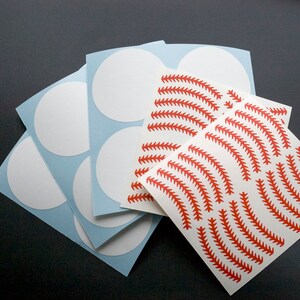 May include: A set of white circle stickers with a sheet of red baseball stitch pattern stickers.