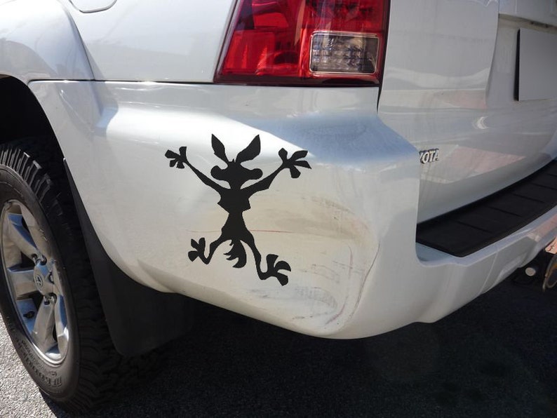 May include: A white SUV with a black silhouette of a coyote sticker on the rear bumper.
