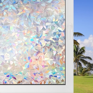 May include: A window film applied to a glass pane, featuring a repeating pattern of overlapping, semi-circular shapes that create a prismatic, iridescent effect with shifting colors of blue, pink, and yellow across the surface.
