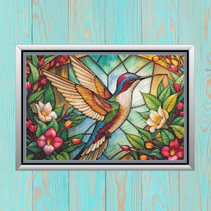 May include: Framed artwork featuring a colorful hummingbird with outstretched wings. The bird is surrounded by flowers and foliage in shades of red, pink, green, and white. The background resembles stained glass, with a silver frame.