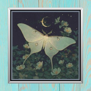 May include: A cross-stitch design featuring a large, pale green Luna moth with detailed wings, set against a dark blue night sky with a crescent moon and stars. White flowers and green foliage surround the moth, creating a serene, nature-inspired scene.
