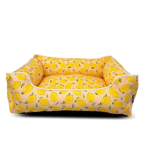 May include: A yellow and white dog bed with a lemon print. The bed has a raised edge and a soft, comfortable interior.