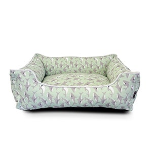 Peut inclure: Un lit pour chien de couleur vert clair avec une bordure blanche et un motif de requins gris. Le lit est rectangulaire et possède un bord surélevé.
