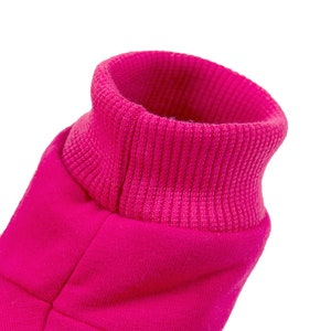 May include: A close-up of a pink fleece jacket with a ribbed collar. The collar is folded down and the fabric is soft and fuzzy.