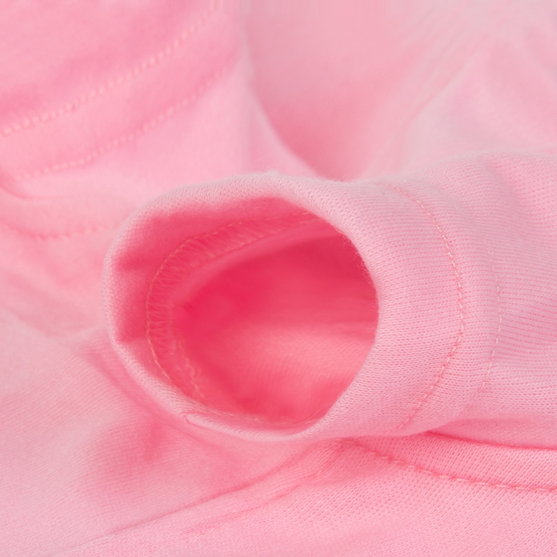 Op de afbeelding: Close-up van een roze stof met een genaaide opening. De stof is zacht en glad.