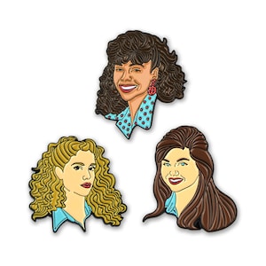 May include: Set of three enamel pins featuring cartoon portraits of women with different hairstyles. The women are wearing blue shirts with white collars. The pins are in a retro style.