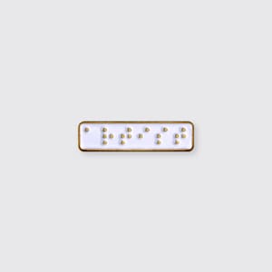 May include: White enamel pin with the word "love" written in braille.