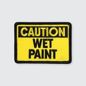 May include: Yellow and black caution sign with the text "CAUTION WET PAINT" in black.