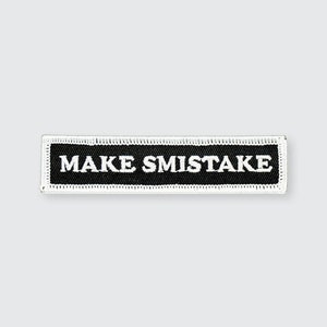 May include: Black and white embroidered patch with white stitching around the edges. The patch says "MAKE SMISTAKE" in white text.