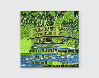 May include: A rectangular enamel pin featuring a vibrant depiction of a bridge over a pond with water lilies. The design uses shades of green, blue, and gold, reminiscent of a famous painting. The pin has a gold border.