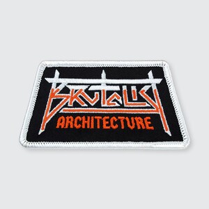 May include: Black and white embroidered patch with the text "ARCHITECTURES" in orange and white. The patch has a white border.