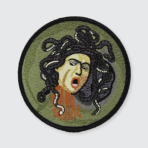 May include: Embroidered patch featuring Medusa's head with snakes for hair, a screaming expression, and blood dripping from her neck. The patch has a green background with a black border.