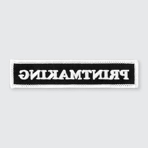 May include: Black embroidered patch with white stitching. The text "remarkable" is written in reverse on the patch.