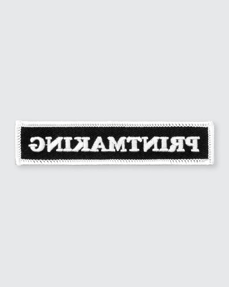 May include: Black embroidered patch with white stitching. The text "remarkable" is written in reverse on the patch.