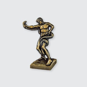 May include: A bronze sculpture of a man wrestling a snake. The man is depicted in a dynamic pose, with his arms outstretched and his legs bent. The snake is wrapped around his body, and its head is raised in a threatening posture.