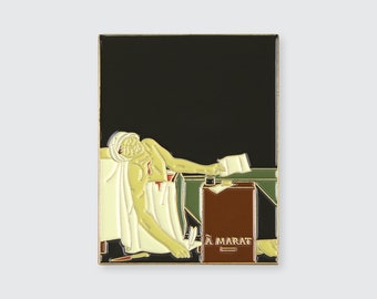 May include: A gold-colored enamel pin depicting a painting of a man lying in a bathtub with a knife in his chest. The man is wearing a white cloth and has a bandage on his head. The text "J. MARAT" is visible on a brown box in the lower right corner of the pin.