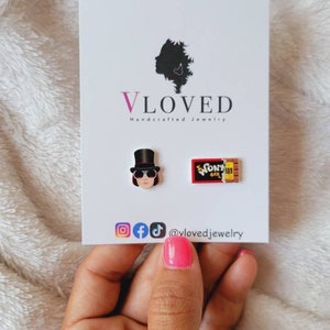 May include: A pair of earrings featuring a Willy Wonka character and a Wonka Bar chocolate bar. The earrings are handmade and are available for purchase on Etsy. @vlovedjewelry